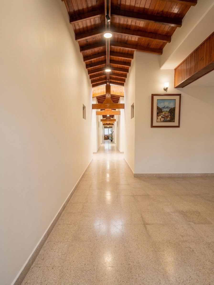 Pasillo central con vigas de madera noble e iluminación focalizada